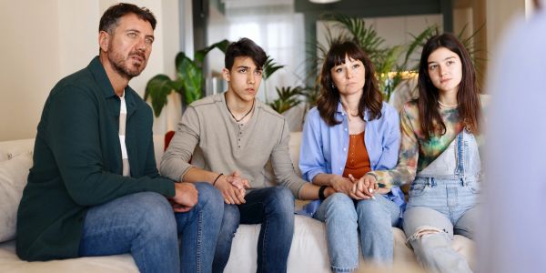 Concerned family holding hands during a serious discussion.
