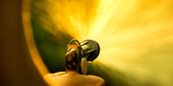 Close-up of a hand holding a garden sprinkler spraying water.