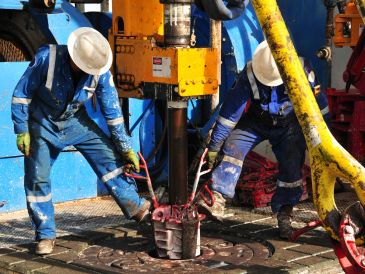 Workers operating heavy machinery at an industrial site.