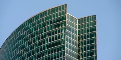 Modern glass skyscraper with curved design against a clear blue sky.