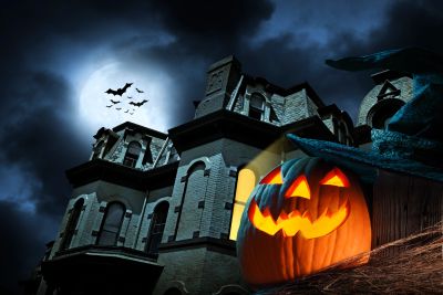 Halloween pumpkin and spooky house under moonlight.
