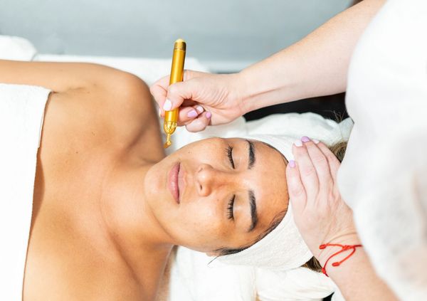 Woman receiving skincare treatment with serums in bottles.