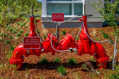 Image of a red backflow preventer in front of building 