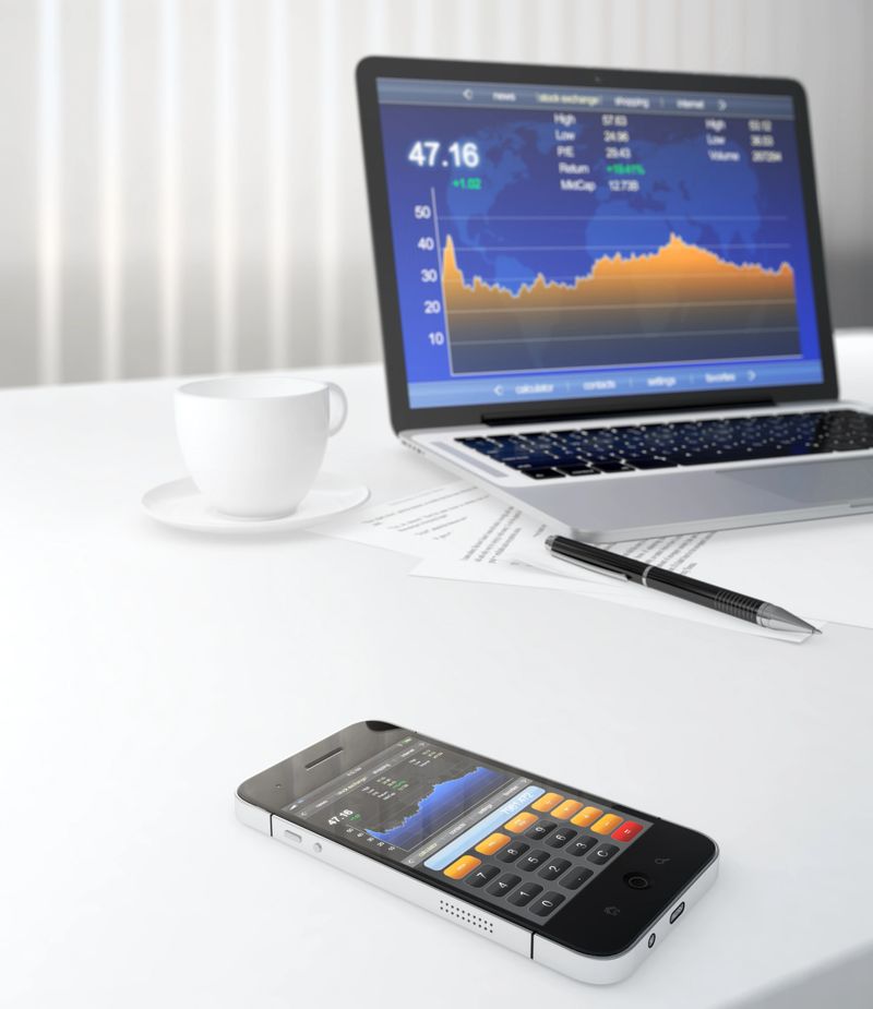 3D illustration of smartphone and laptop on table with stock market application on screen