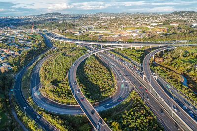 Aerial view of a complex highway interchange surrounded by greenery and urban areas.