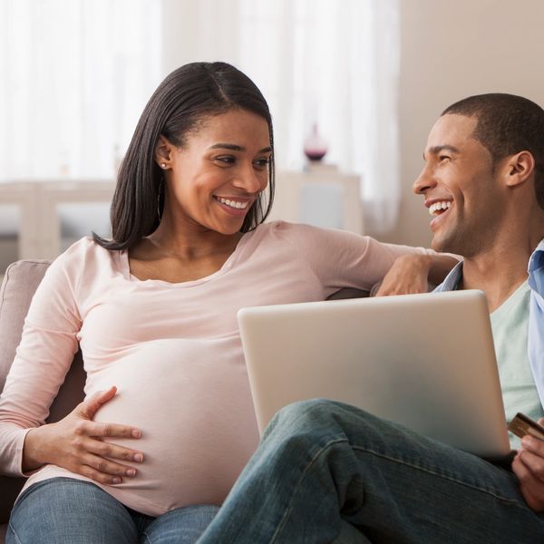 Pregnant woman and partner happily shopping online together.