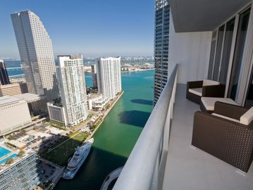 Balcony view of city skyscrapers and waterway.