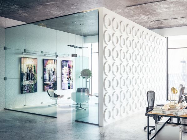 Modern office space with glass-walled meeting room and artistic decor.
