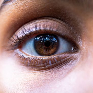Close-up of a brown eye with detailed skin texture and reflections.