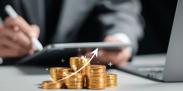 Stacked coins with financial growth graph in the background.