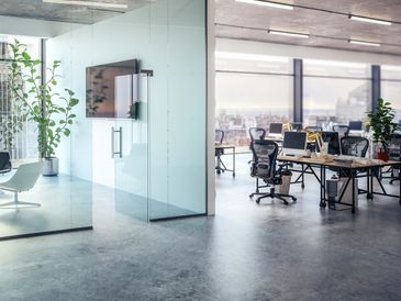 Modern office space with glass walls and desks.
