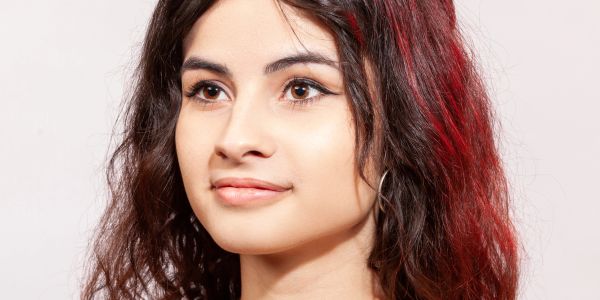 Portrait of a young woman with curly hair and natural makeup.