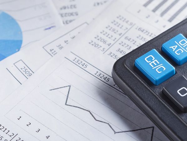 Calculator and financial charts on paper for analysis.