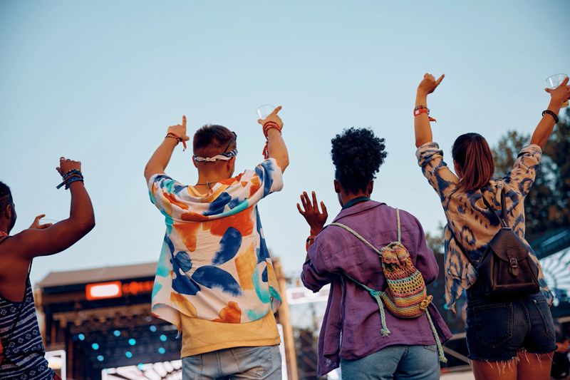 Back view of festival goers enjoying in music concert during summer.
