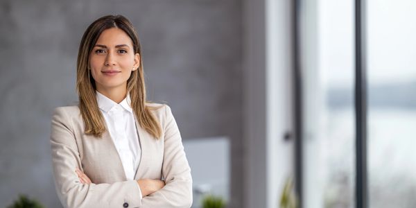 Confident woman in a beige blazer smiling.
