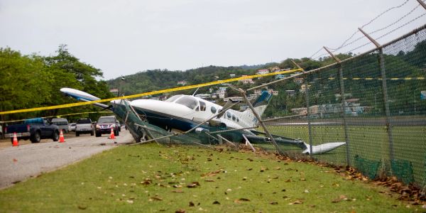 Small plane crashed through a chain-link fence near a road.