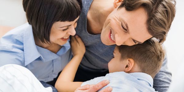 Happy parents embracing their child in a warm family moment.