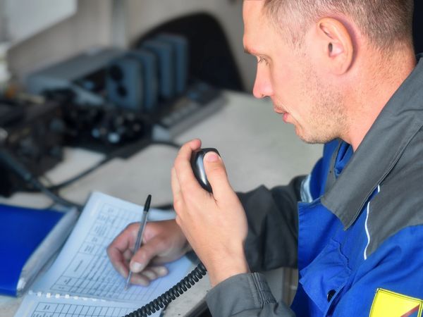 Man communicating on a radio while writing notes.