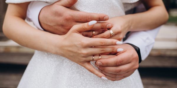 Newlyweds holding hands, showing wedding rings.