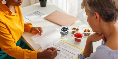 Two women reviewing documents at a table with healthy snacks.
