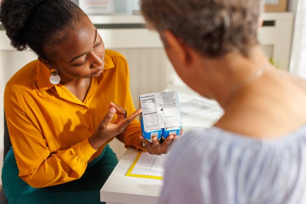 Woman explaining nutrition facts on product packaging to another person.