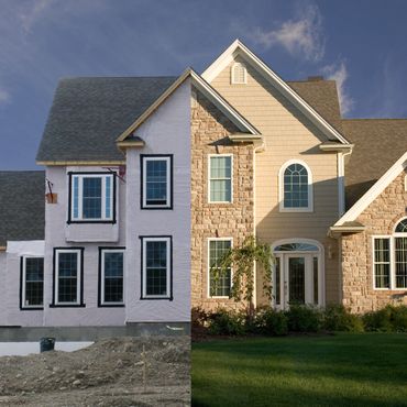 Half of a house under construction, half finished with stone and siding.