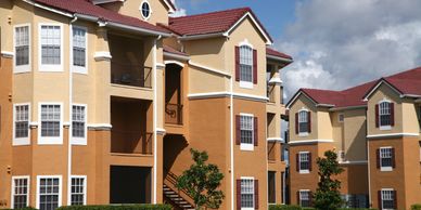 Sunny day view of modern apartment buildings with red roofs and well-kept lawns.