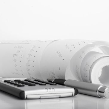 Calculator, pen, and rolled financial printout on a reflective surface.