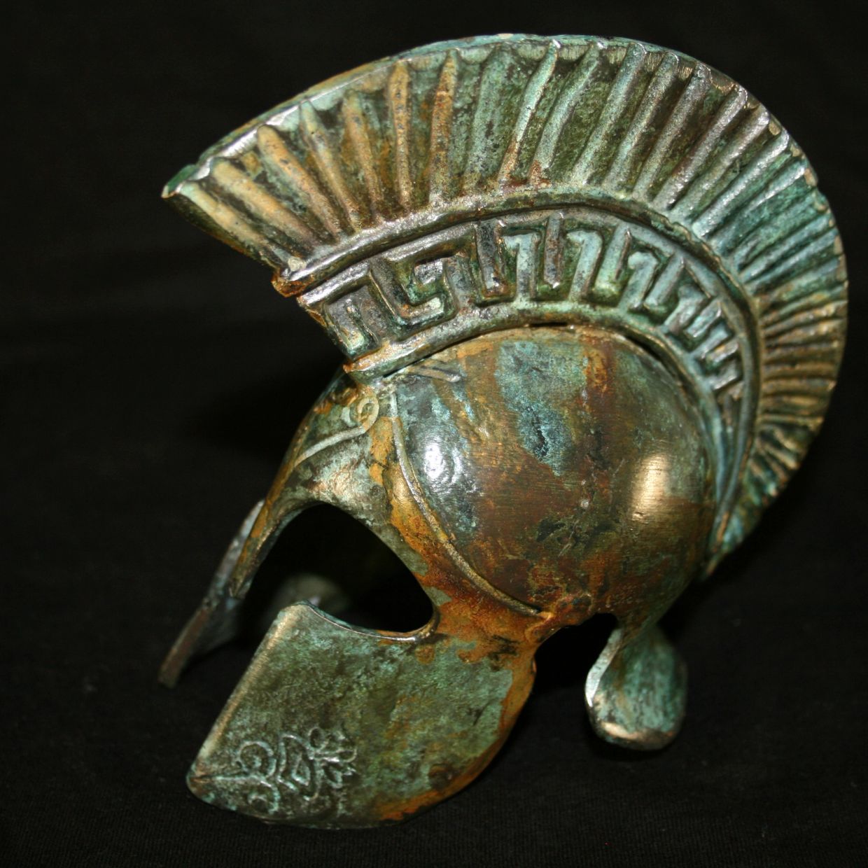 Ancient bronze Spartan helmet with decorative crest and patina.