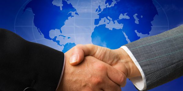 Two business professionals shaking hands with a world map background.