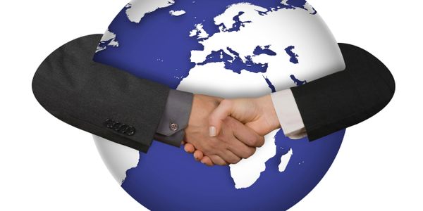 Two business people shaking hands around a globe symbolizing global cooperation.