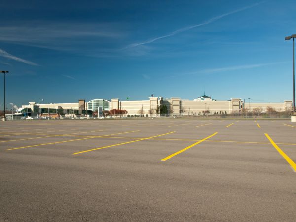 Grand parking vide devant un grand centre commercial.
