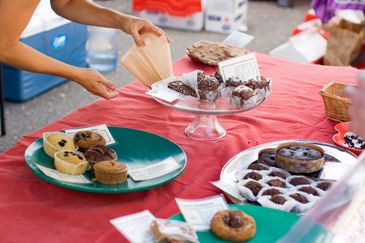 Person taking baked goods from a table at a market.