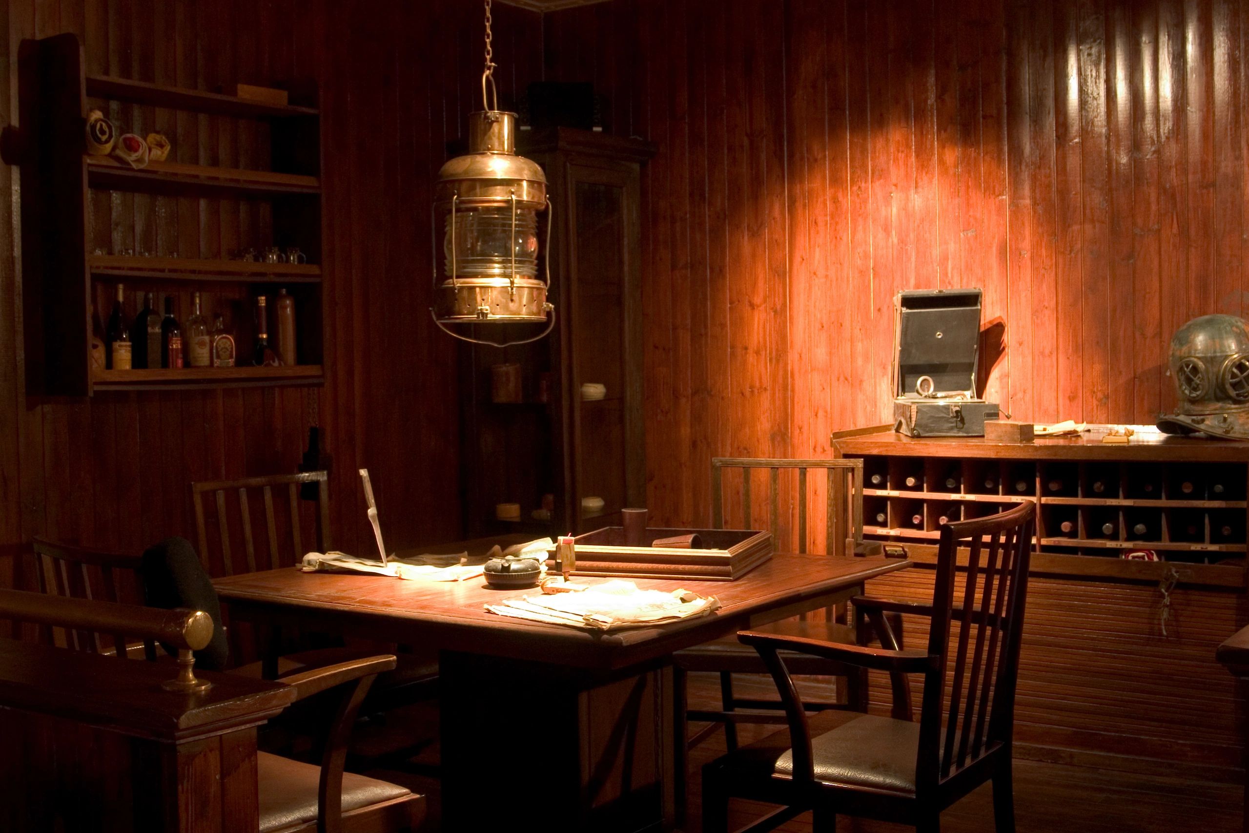 Wood-paneled room with lantern, documents, and vintage diving helmet.