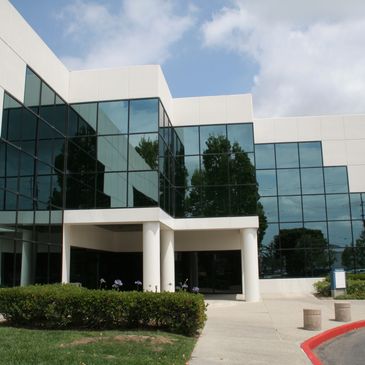 Modern office building with reflective glass windows and white pillars.