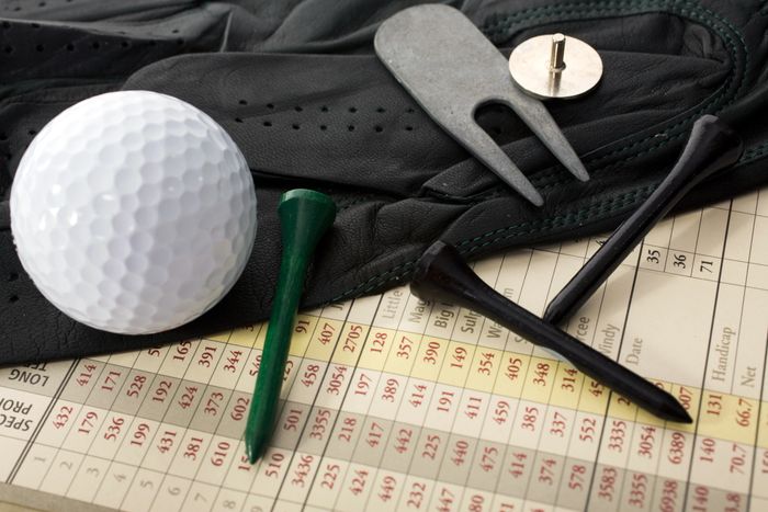 Gloved hand placing a golf ball near a golf club in dramatic lighting.