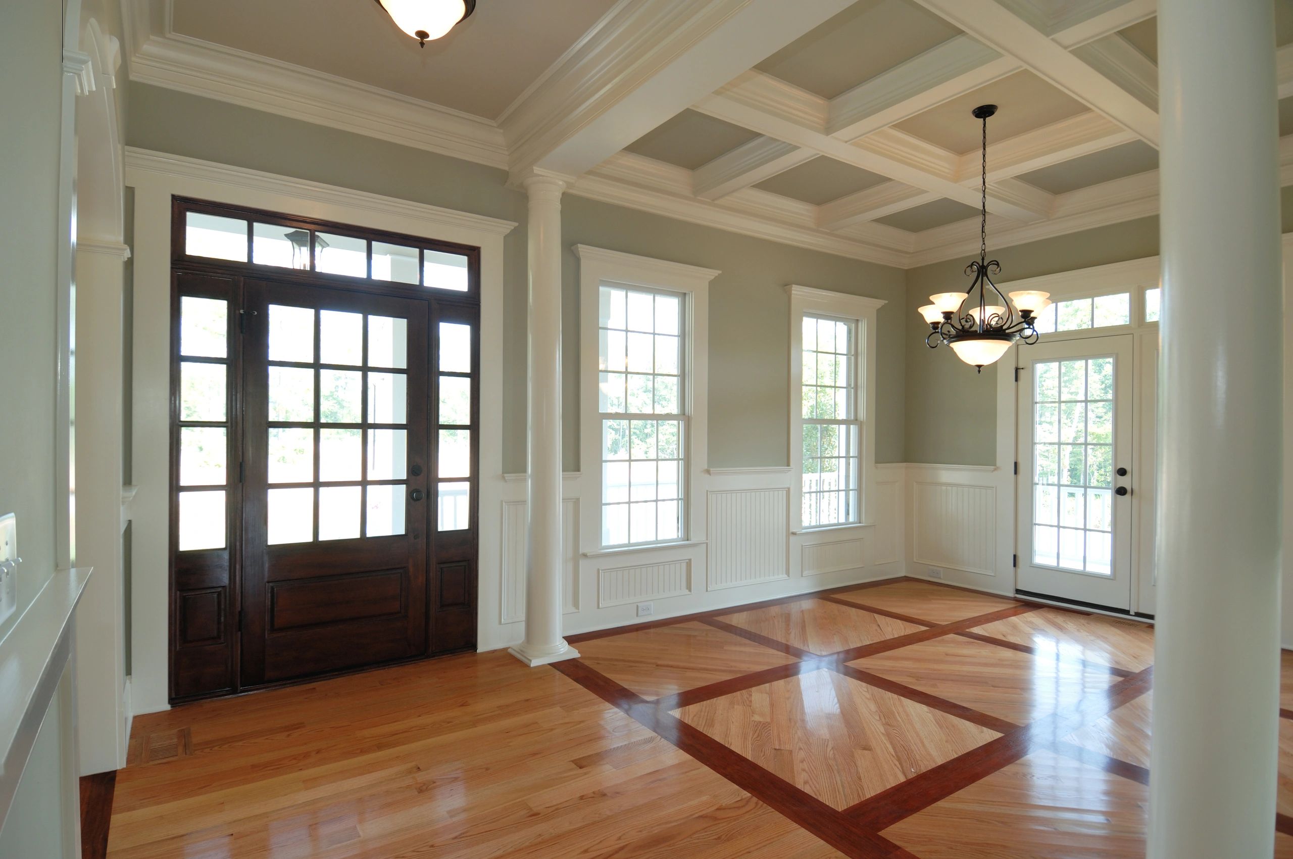 Elegant foyer with coffered ceiling and patterned hardwood floor.