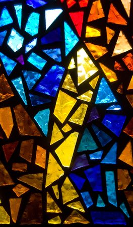 Colorful stained glass windows illuminate empty church pews.