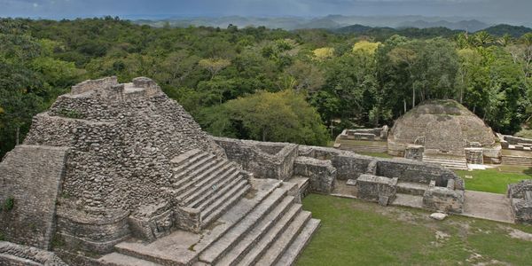 Ancient stone pyramids surrounded by lush forest and mountains.