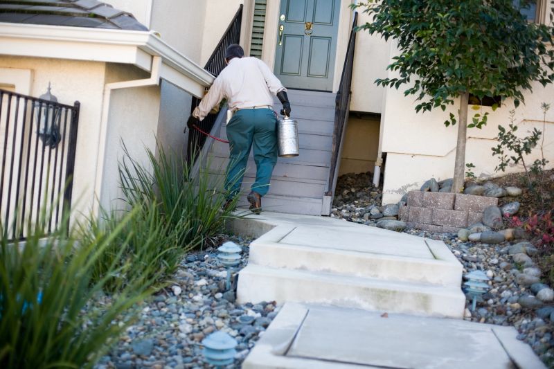 Pest control worker treats ground around the house.