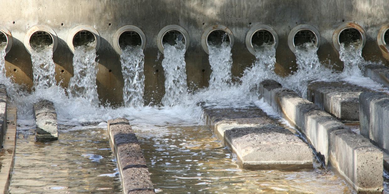 Water flowing from multiple pipes into a drainage system.