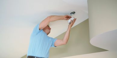 A man installs a ceiling light fixture.