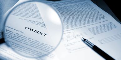 Magnifying glass highlighting the word 'CONTRACT' on a document.