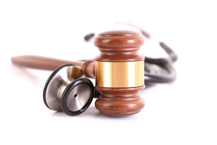 A judge's gavel resting next to a stethoscope on a white background.
