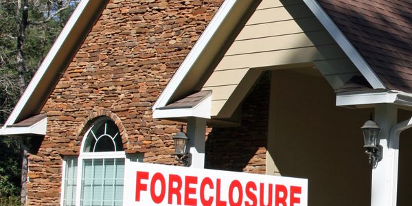 A house with a large foreclosure sign in front of it.