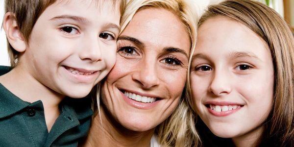 Happy mother with her young son and daughter smiling closely together.
