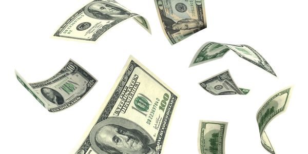 Several US dollar bills floating in midair against a white background.