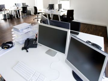 Modern office workspace with multiple computer monitors and office supplies.