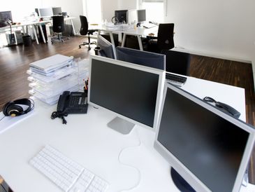Modern office workspace with dual monitors and organized desks.