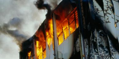 Building engulfed in flames with thick black smoke.